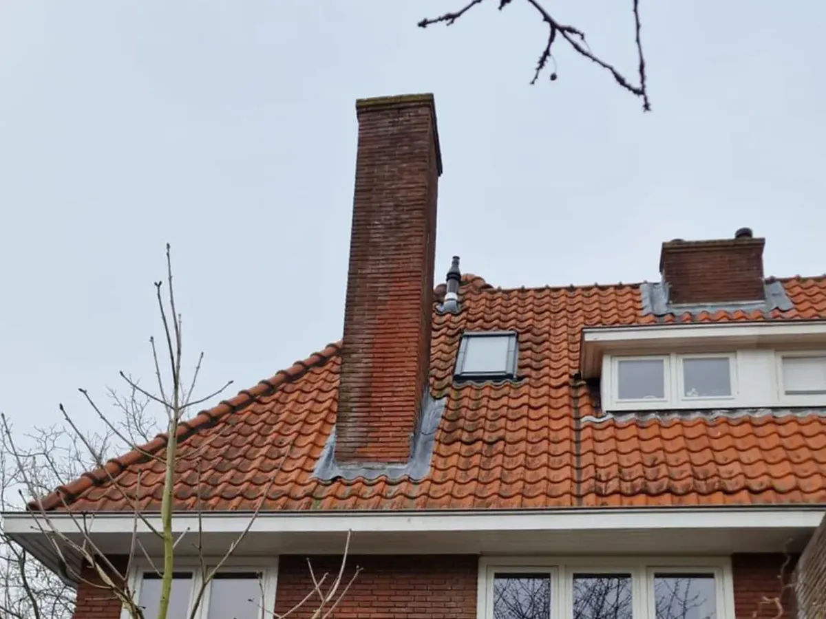 Een gemetselde schoorsteen op een pannendak.